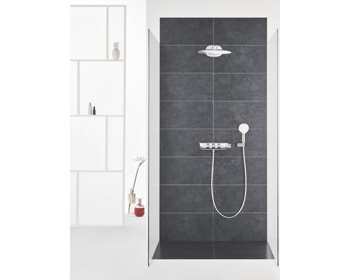 Koupelna se sprchou, hlavovou sprchou, ruční sprchou a armaturou před tmavým obkladem