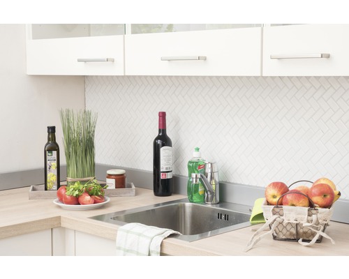 Kuchyňská scéna s umyvadlem, baterií a různým kuchyňským náčiním na pracovní desce.