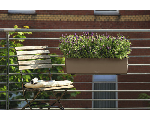 Scéna s truhlíkem s rostlinami zavěšeným na zábradlí a skládací židlí s polštářem a časopisem