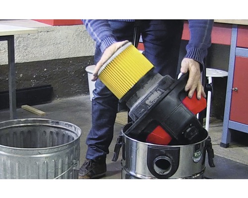 Osoba likviduje filtr vysavače do odpadkového koše