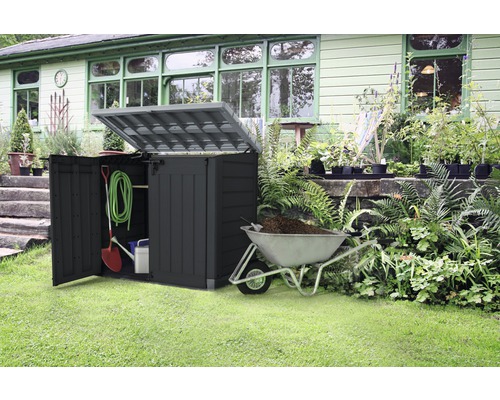 Zahradní scéna s otevřeným boxem na nářadí, zahradním nářadím a kolečkem naplněným zeminou.