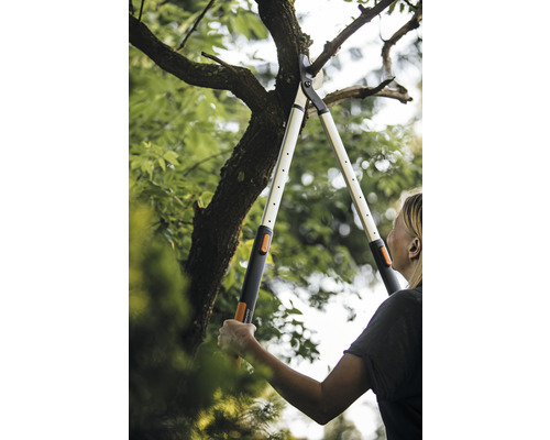 Žena stříhá větve stromů pomocí pákových nůžek na větve