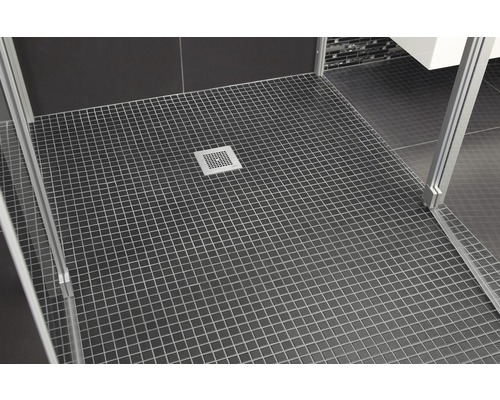 Koupelna s tmavými čtvercovými dlaždicemi, sprchovým koutem a odtokem