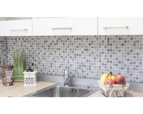 Kuchyňská scéna s mozaikovými obklady, dřezem a dekorativními prvky.