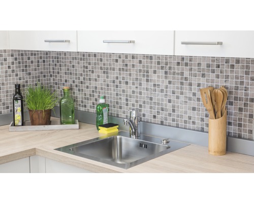 Nerezový kuchyňský dřez s baterií na pracovní desce ve světlé kuchyni s mozaikovými obklady