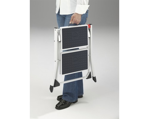 Skládací schůdky se dvěma stupni, které nese osoba.