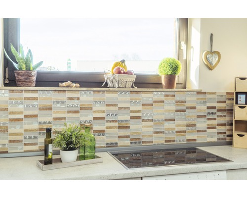 Kuchyňská scéna s mozaikovými obklady na zdi, pracovní deska s rostlinami a varná deska