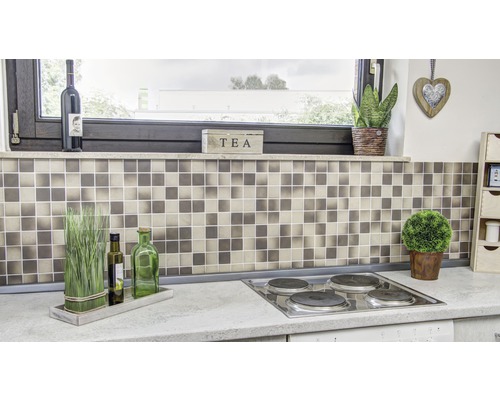 Kuchyňská scéna s mozaikovými dlaždicemi, varnou deskou a dekorativními prvky.