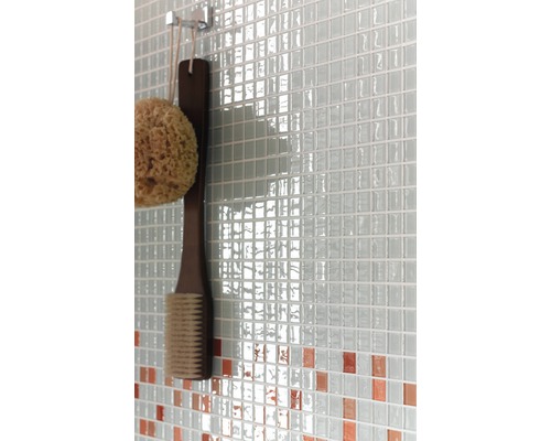 Detailní záběr stěny s mozaikovými obklady, koupelnovou houbou a kartáčem