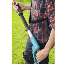 Muž obsluhuje elektrické nůžky na živý plot na zahradě.