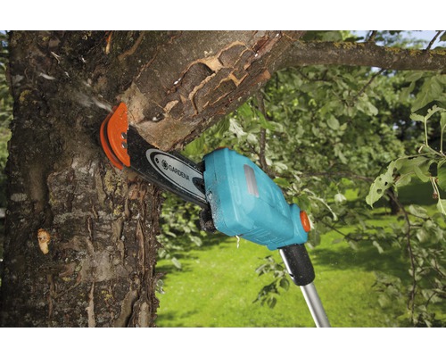 Akumulátorová tyčová pila Gardena řeže větev na stromě.