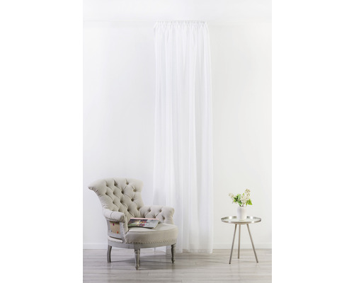 Světlá místnost s křeslem, odkládacím stolkem s vázou květin a závěsem