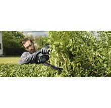 Muž stříhá živý plot pomocí nůžek na živý plot