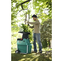 Muž používá zahradní drtič značky Bosch na zahradě.