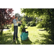 Muž plní zahradní drtič na zahradě větvemi.