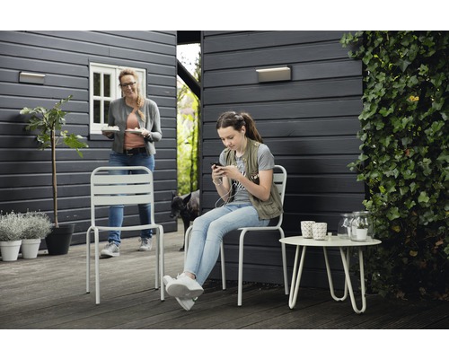 Zahradní scéna s kovovými židlemi a odkládacím stolem na terase