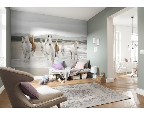 Obývací pokoj s fototapetou zobrazující skupinu cválajících koní na pláži, plus křeslo a koberec