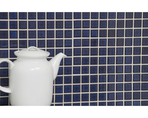 Stěna z mozaikových dlaždic s bílými spárami a bílá čajová konvice