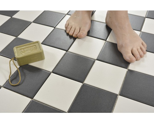 Čtvercové dlaždice v šachovnicovém vzoru s kusem mýdla a chodidly