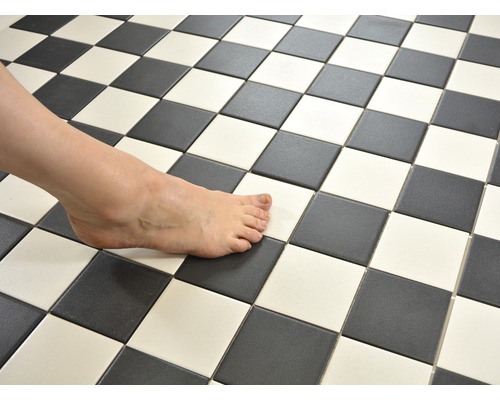 Šachovnicový vzor z černých a bílých dlaždic s bosou nohou