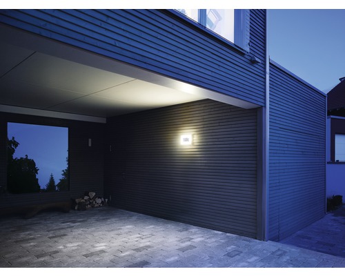 Exteriér moderně navrženého domu s venkovním osvětlením a dlážděnou příjezdovou cestou