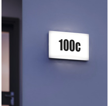Osvětlená dveřní tabulka s číslem 100c na zdi