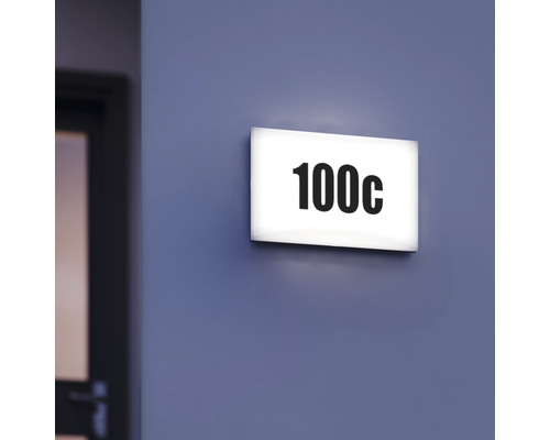 Osvětlená dveřní tabulka s číslem 100c na zdi