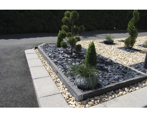 Upravená zahrada s rostlinami, kameny a obrubníky trávníku