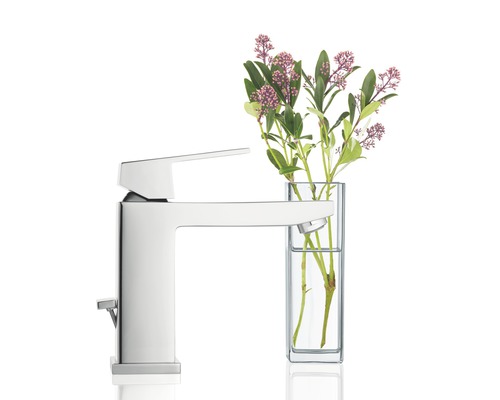 Lesklá armatura vedle vázy s květinami.