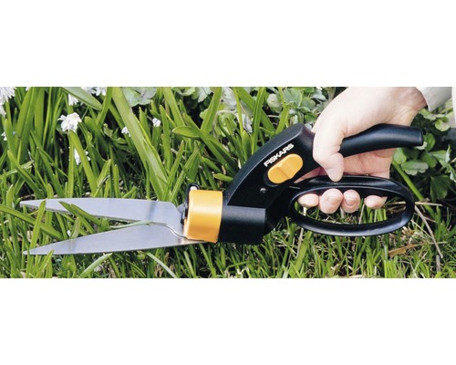 Osoba stříhá trávu nůžkami na trávu Fiskars.