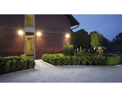 Osvětlená budova se zahradou a dlážděnou cestou