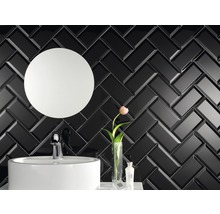 Koupelna s černým obkladem do rybí kosti, umyvadlem a kulatým zrcadlem