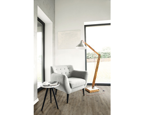 Světlý obývací pokoj s křeslem, stojací lampou a odkládacím stolkem na podlaze