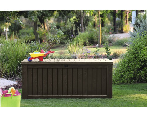 Zahradní scéna s velkým, tmavým zahradním boxem pod vozíkem na hračky.