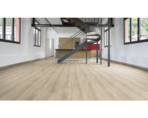 Světlá laminátová podlaha v místnosti se točitým schodištěm a kuchyňským koutem