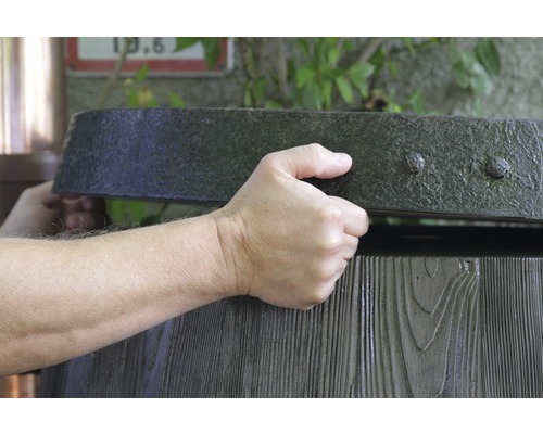 Osoba otevírá dřevěnou nádrž na dešťovou vodu