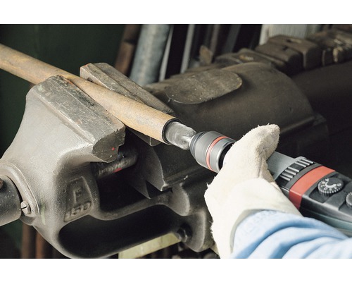 Kovová trubka v svěráku opracovaná brusným nástrojem