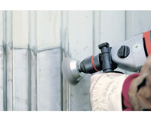 Osoba používá brusku s kartáčovým nástavcem k úpravě povrchu.