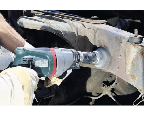 Osoba používá vrtačku s drátěným kartáčem k čištění kovu.