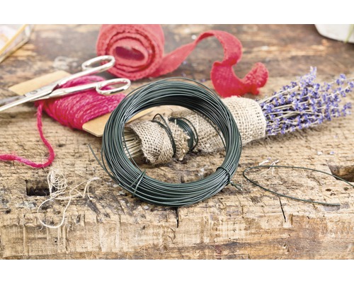 Role zeleného floristického drátu vedle levandule a dárkové stuhy na dřevěném stole