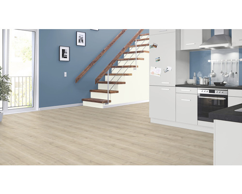 Světlá místnost s laminátovou podlahou, schodištěm a kuchyňskou linkou