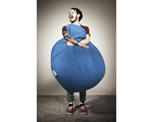 Muž objímá modrý sedací vak v interiéru