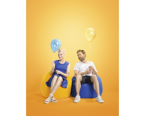Muž a žena sedí na sedacích vacích s balónky.