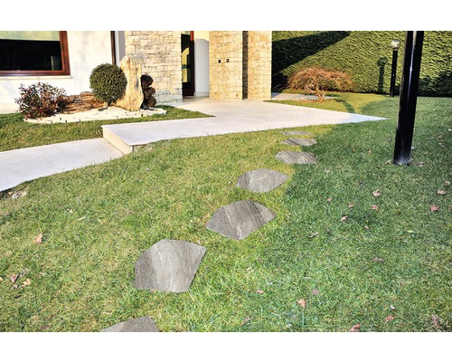 Venkovní fotografie zahrady s trávníkem a kamennými deskami jako chodník k domu.