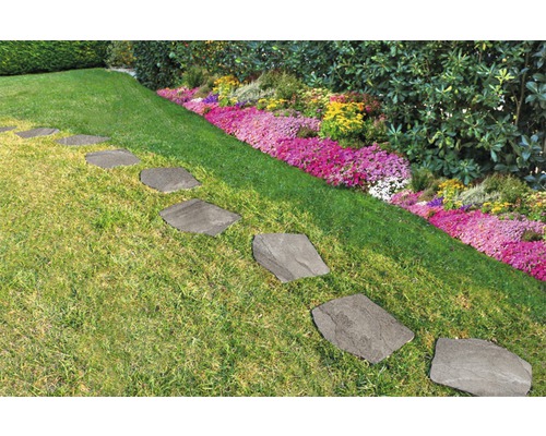 Kamenné nášlapné desky v zahradní cestě mezi trávníkem a květinovým záhonem