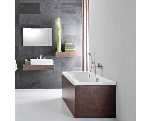 Koupelna s vanou, umyvadlem, zrcadlem a policemi před šedou kamennou zdí