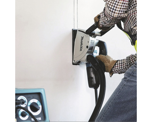 Muž používá drážkovací frézu Makita k frézování drážek do zdi.