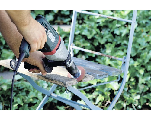 Osoba brousí dřevo bruskou na židli.