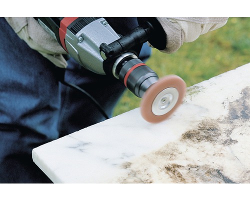 Osoba leští kamenný povrch pomocí leštičky.