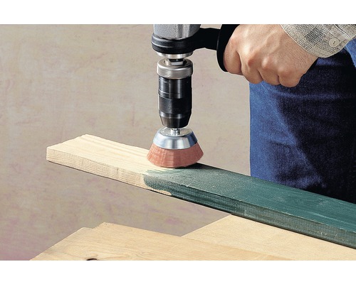 Vrtačka s kartáčovým nástavcem brousí dřevěnou desku.